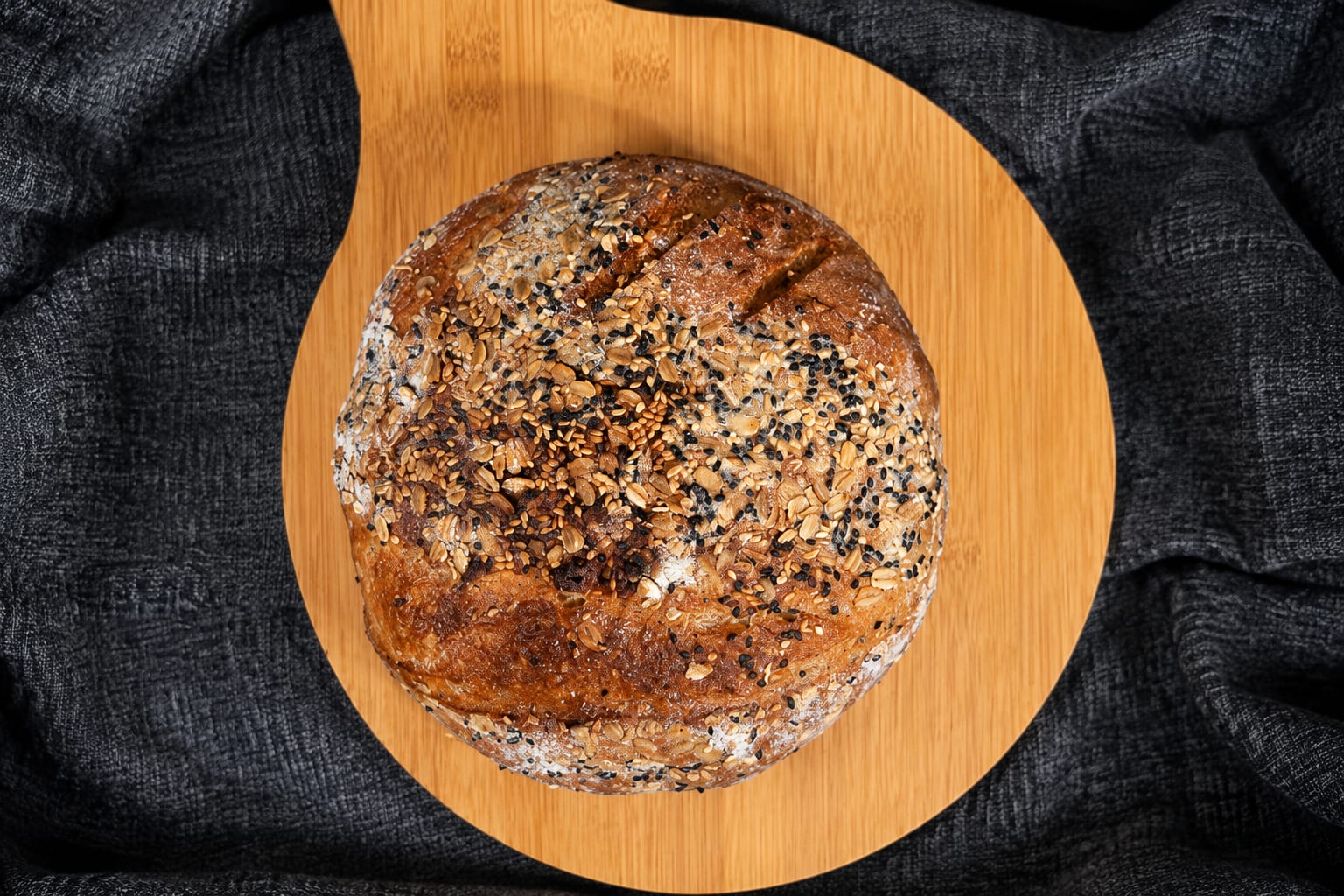 Seeded round sourdough loaf on a wooden board